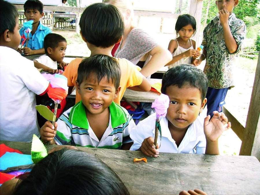 Children doing paper craft activity in open-air classroom