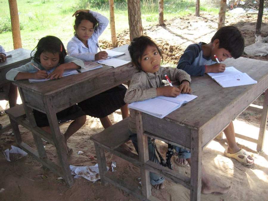 Students writing in notebooks at wooden school desks