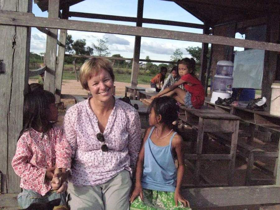 Volunteer sitting with children inside wooden school building