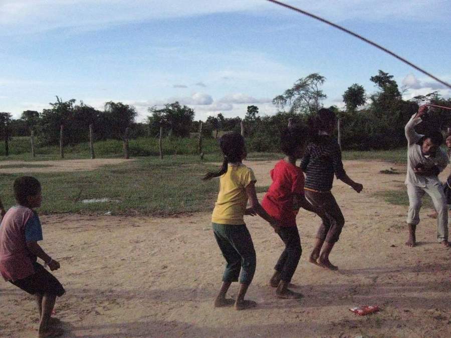 Children playing volleyball on dirt field in village