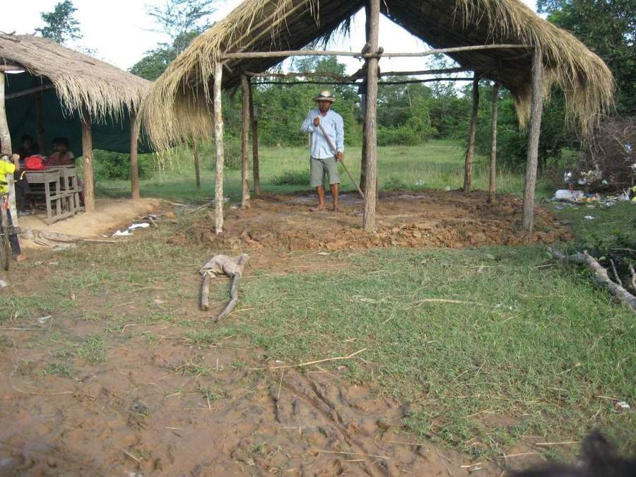 Man standing under thatched roof structure during construction