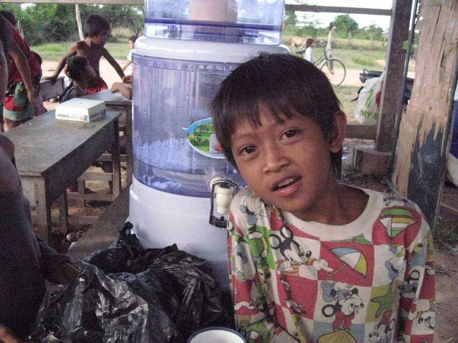 Young boy standing next to water dispenser in classroom