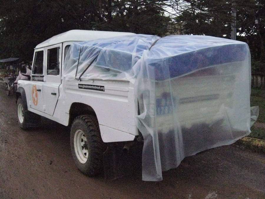 White GSO Land Rover with covered cargo on muddy road