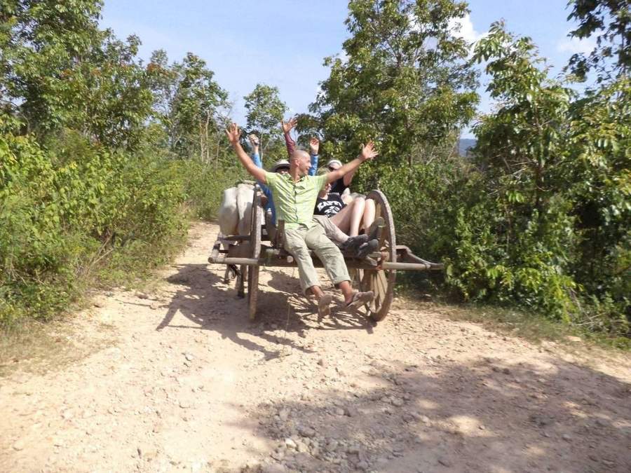 Volunteers riding wooden cart on rocky jungle road