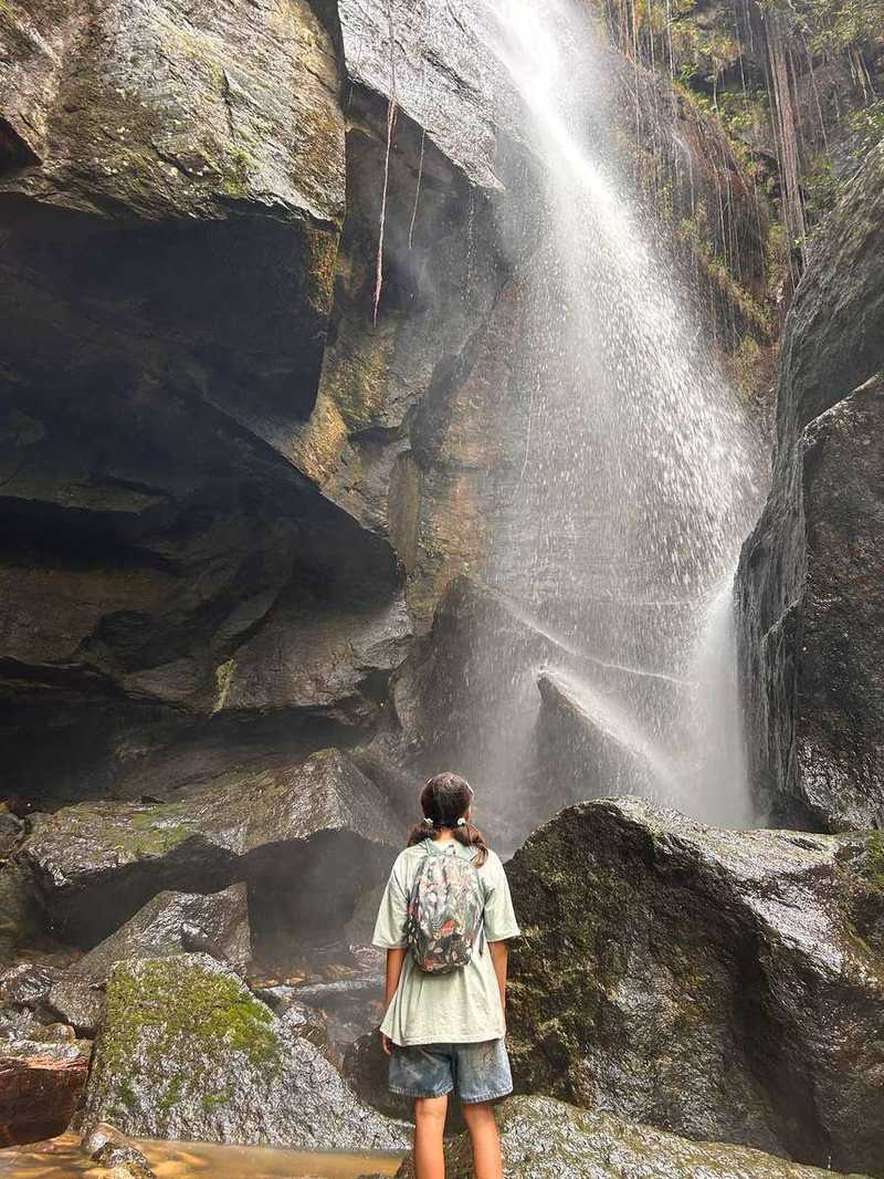 Person standing at base of tropical waterfall