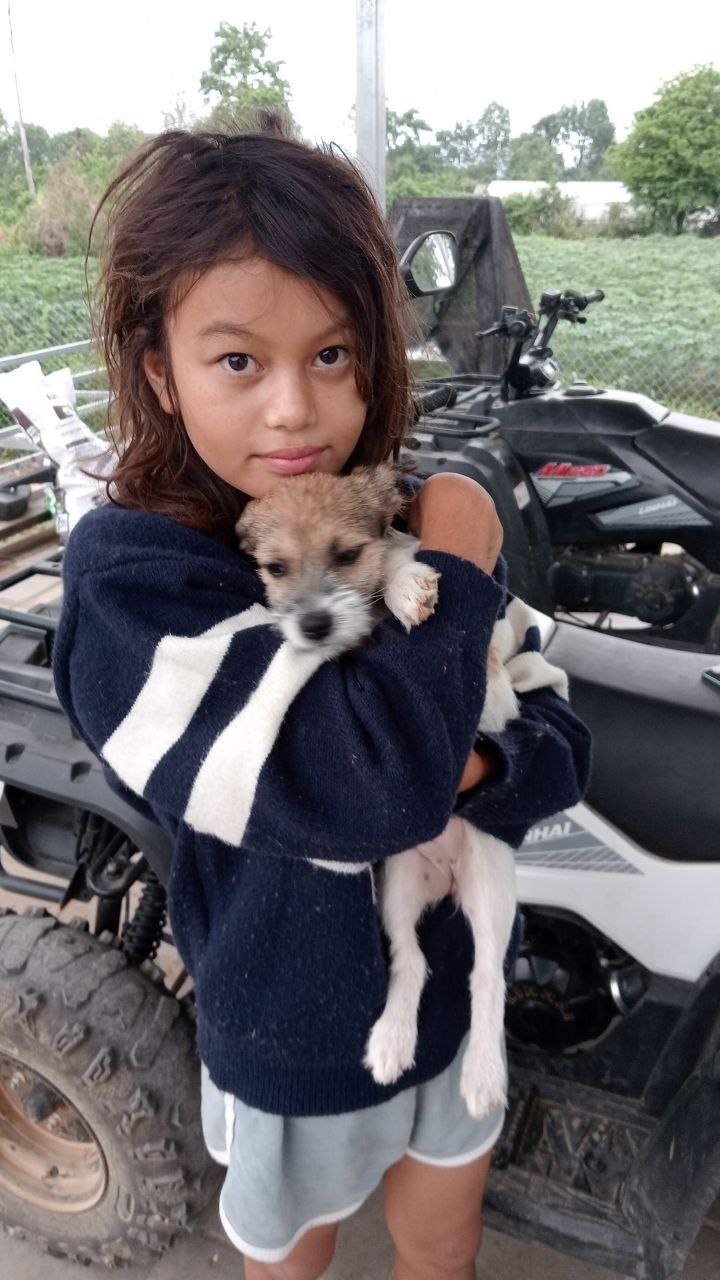 Young girl holding fluffy puppy next to ATV