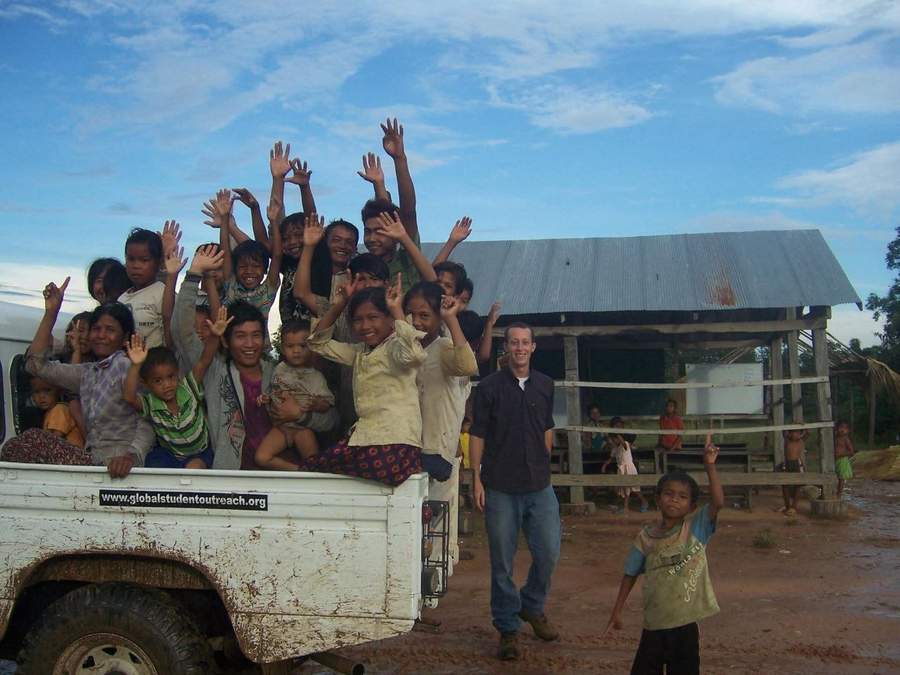 Group of children waving from pickup truck with volunteer