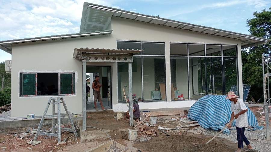 Building under construction with workers smoothing ground