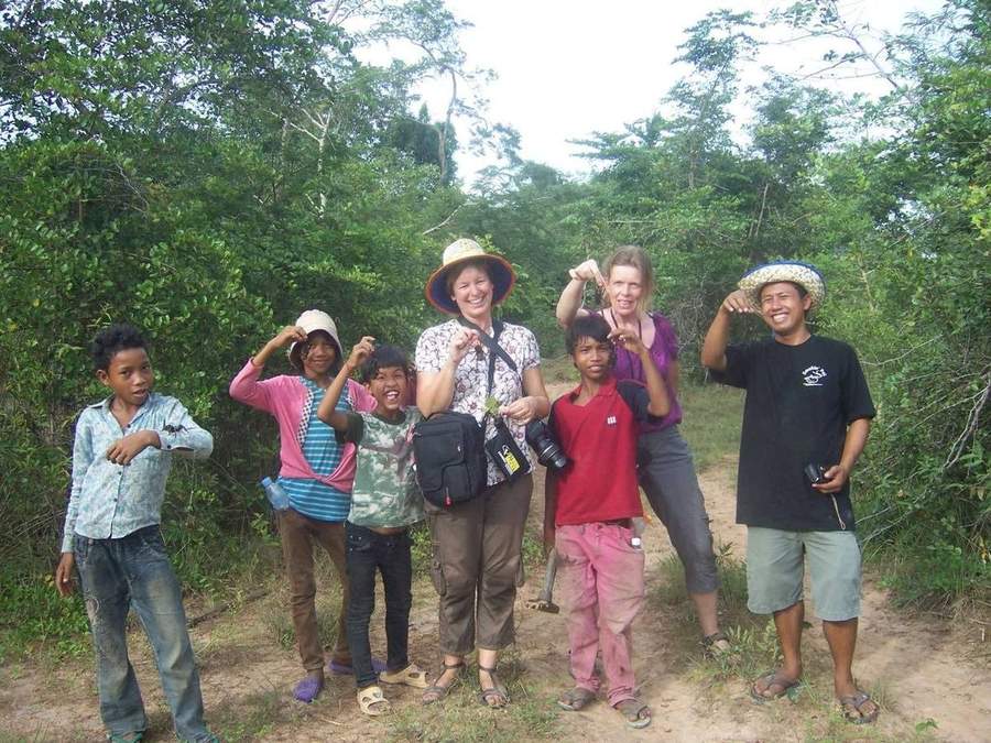 Group of volunteers and local children posing on forest trail