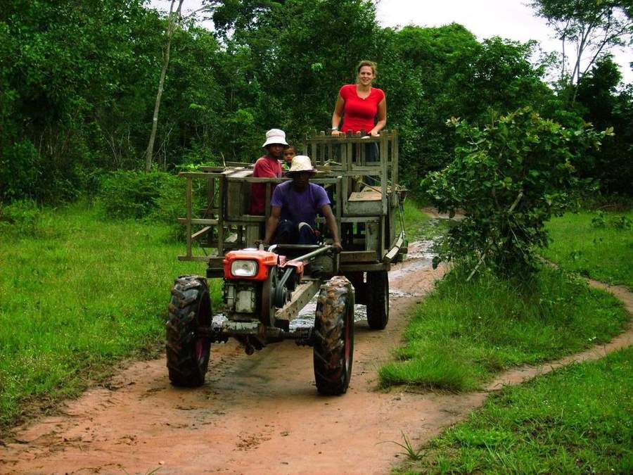 People riding tractor cart on muddy dirt road