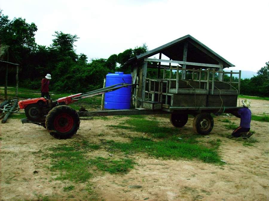 Red tractor with wooden trailer and blue water tank
