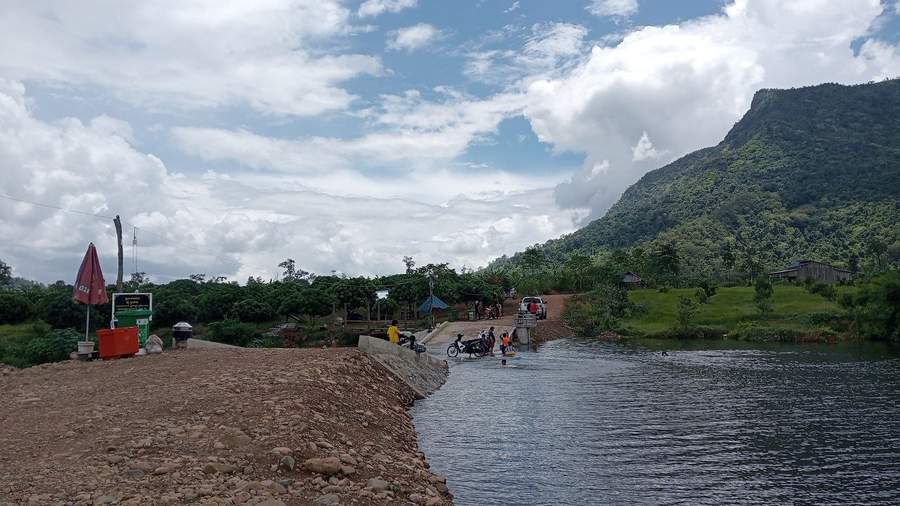 Motorcycle being pushed through river at low water crossing