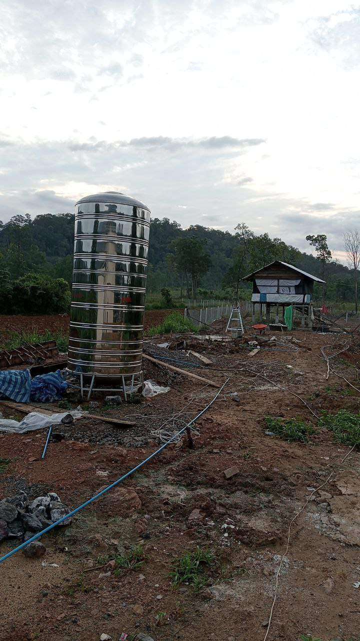 Stainless steel water tank at construction site with small wooden building