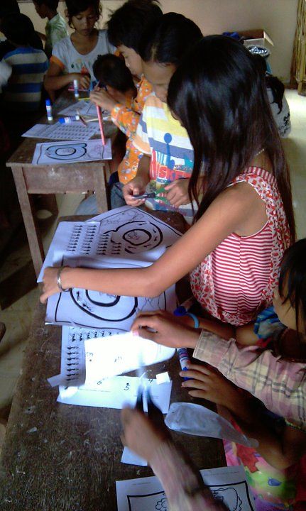Children at desk doing art activity with coloring pages