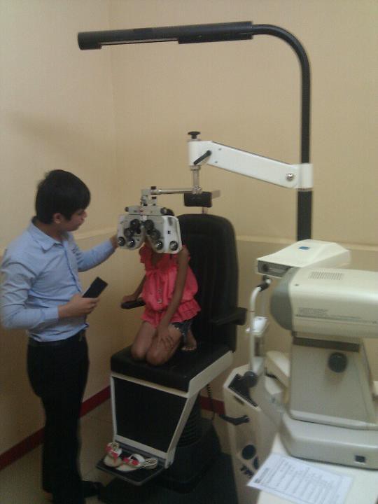 Child sitting in optometrist chair with eye exam equipment