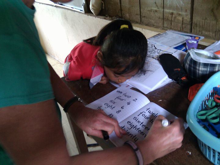 Adult teaching child to write numbers in notebook