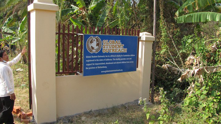 Blue Global Student Outreach sign on gate with man pointing