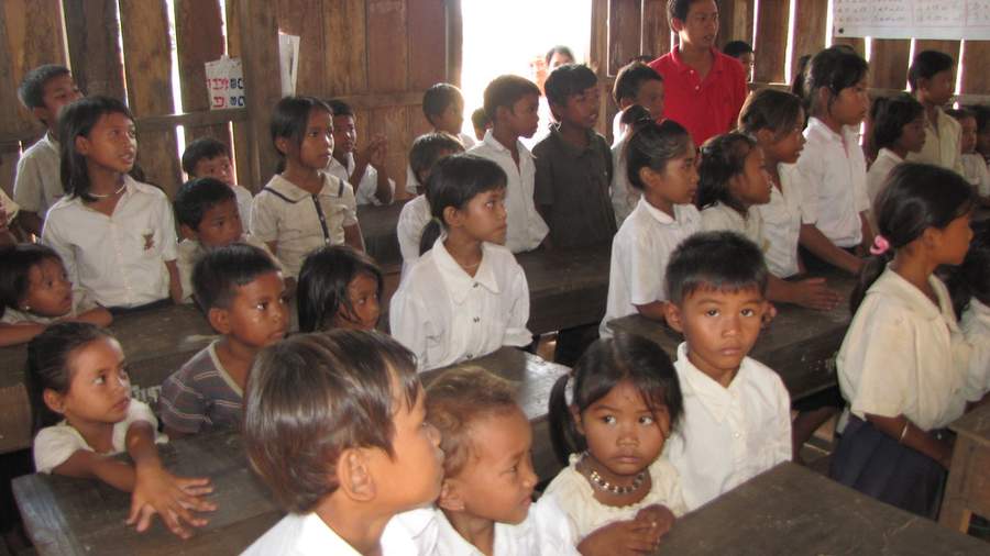 Students in uniforms sitting at desks in wooden classroom