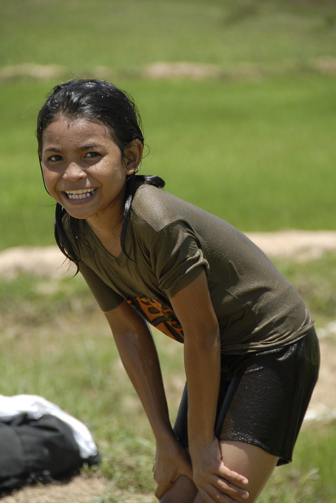Girl covered in water spraying from hose smiling