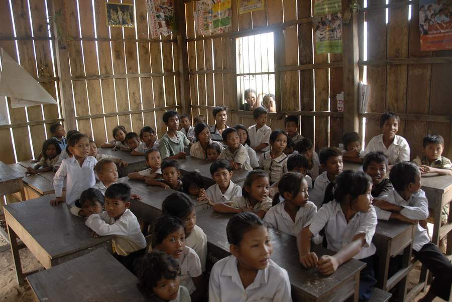 Students in uniforms sitting at desks in wooden classroom