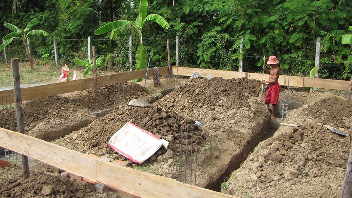 Man standing in foundation trench with wooden formwork