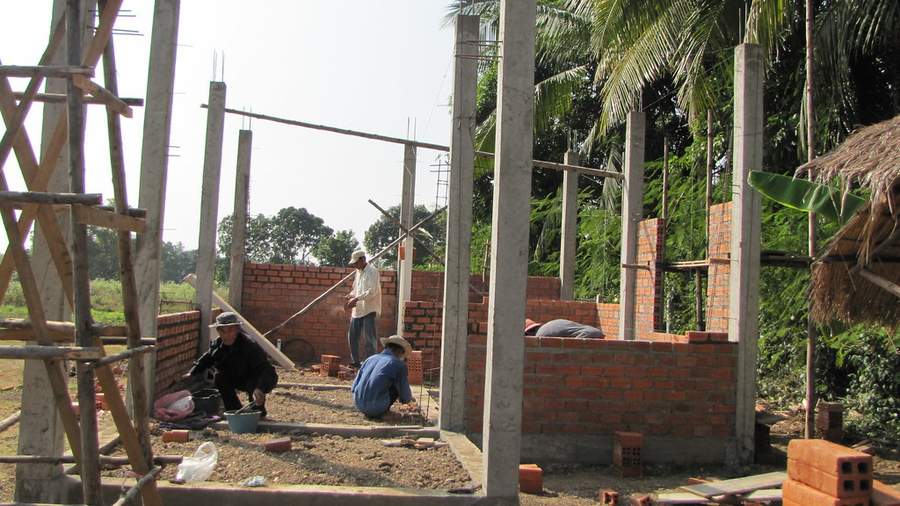 Workers building brick walls with concrete pillars at different angle