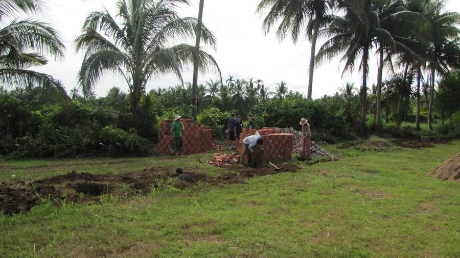 Workers at construction site with brick piles and palm trees