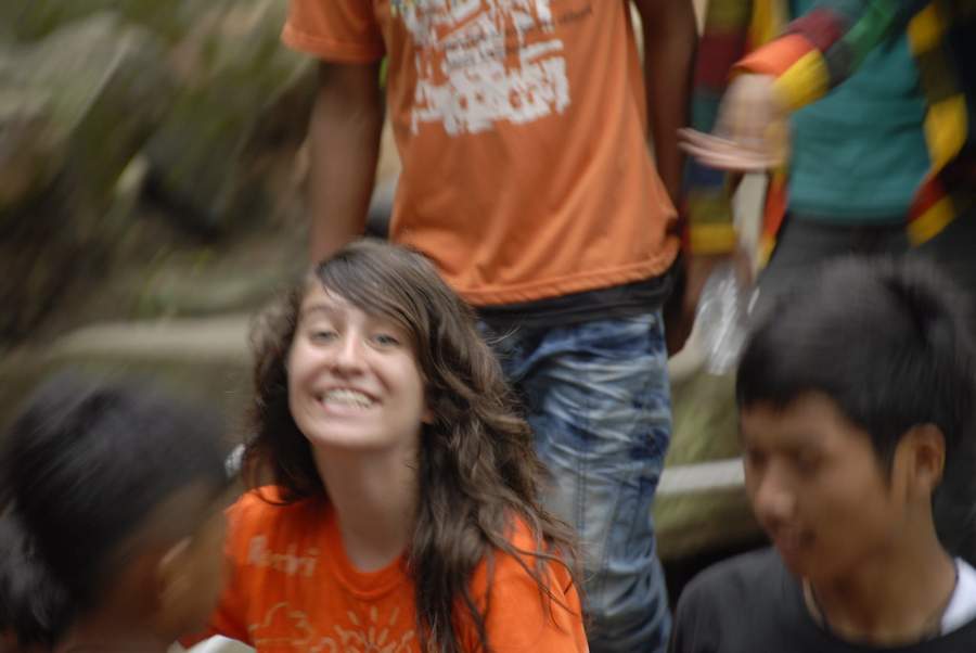 Young woman in orange shirt smiling in crowd