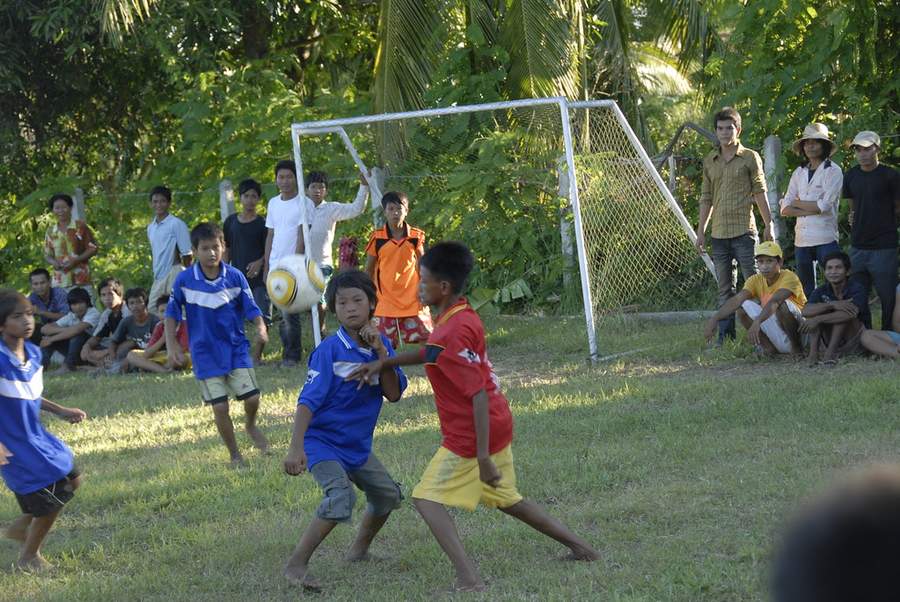 Children playing soccer near goal with spectators