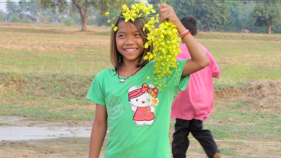 Girl in green Hello Kitty shirt with yellow flower crown in field