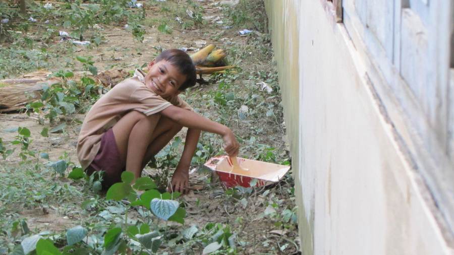 Boy crouching painting building wall