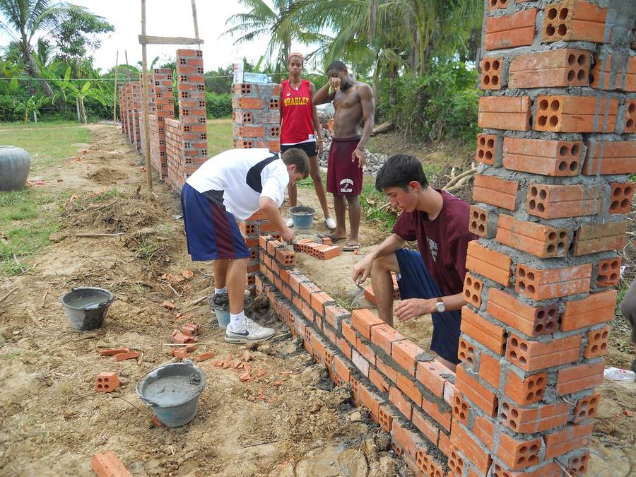 Volunteers and workers building brick wall at construction site