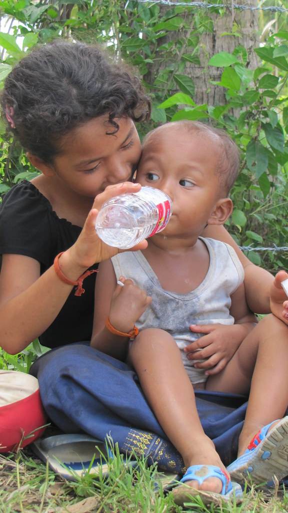 Volunteer giving baby water from bottle
