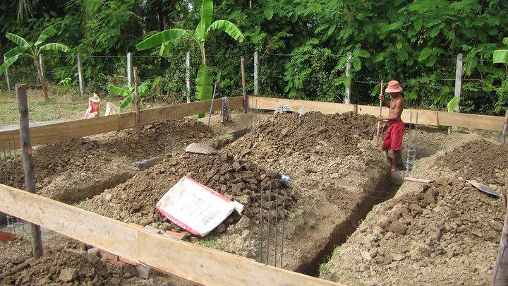Worker digging foundation trench for building