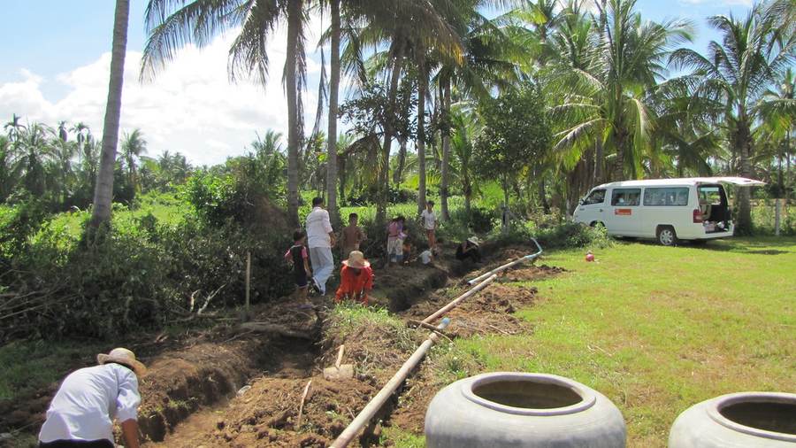 Community members working on trench near white van