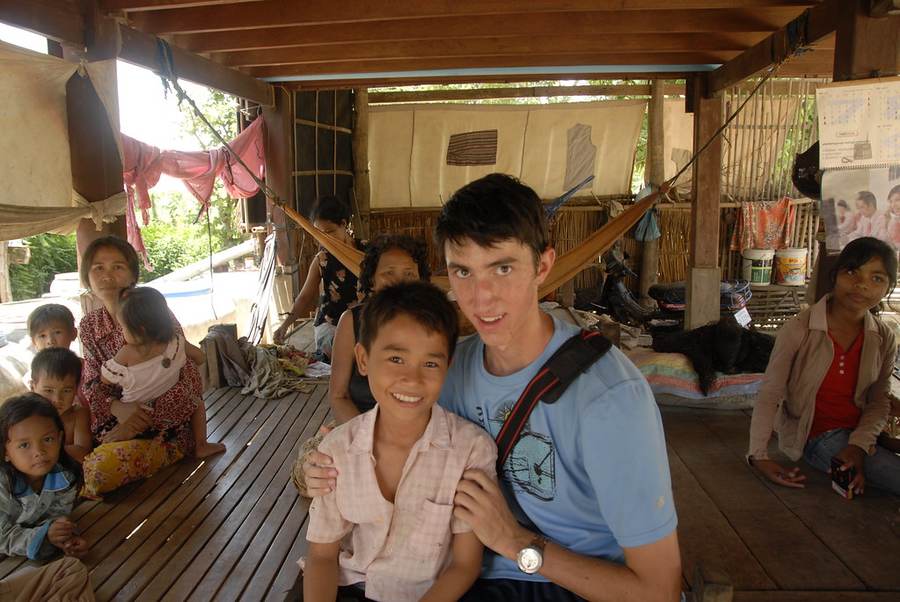 Volunteer sitting with Cambodian family in wooden house