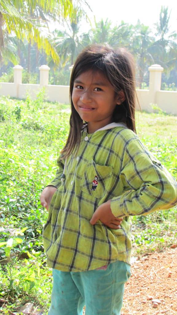 Young girl in green plaid shirt smiling with palm trees
