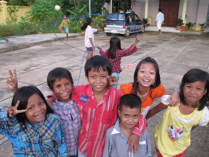 Group of smiling Cambodian children with jump rope in courtyard