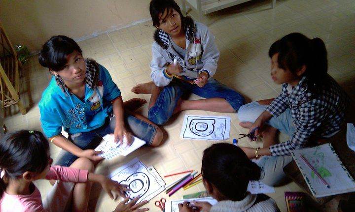 Group of girls sitting on floor coloring and cutting paper crafts