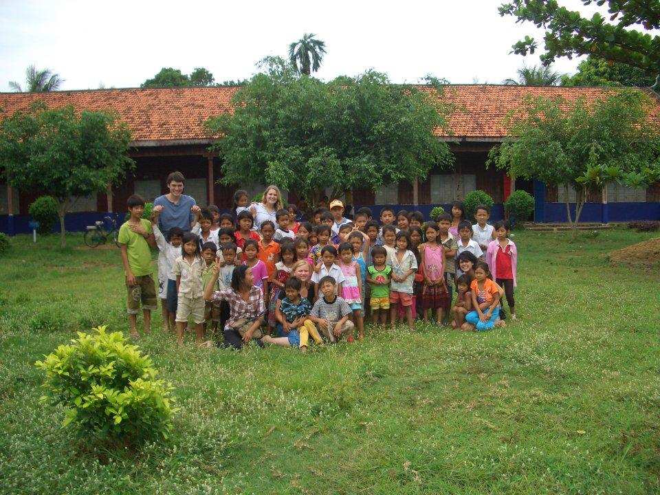 Volunteers with school children in front of the school
